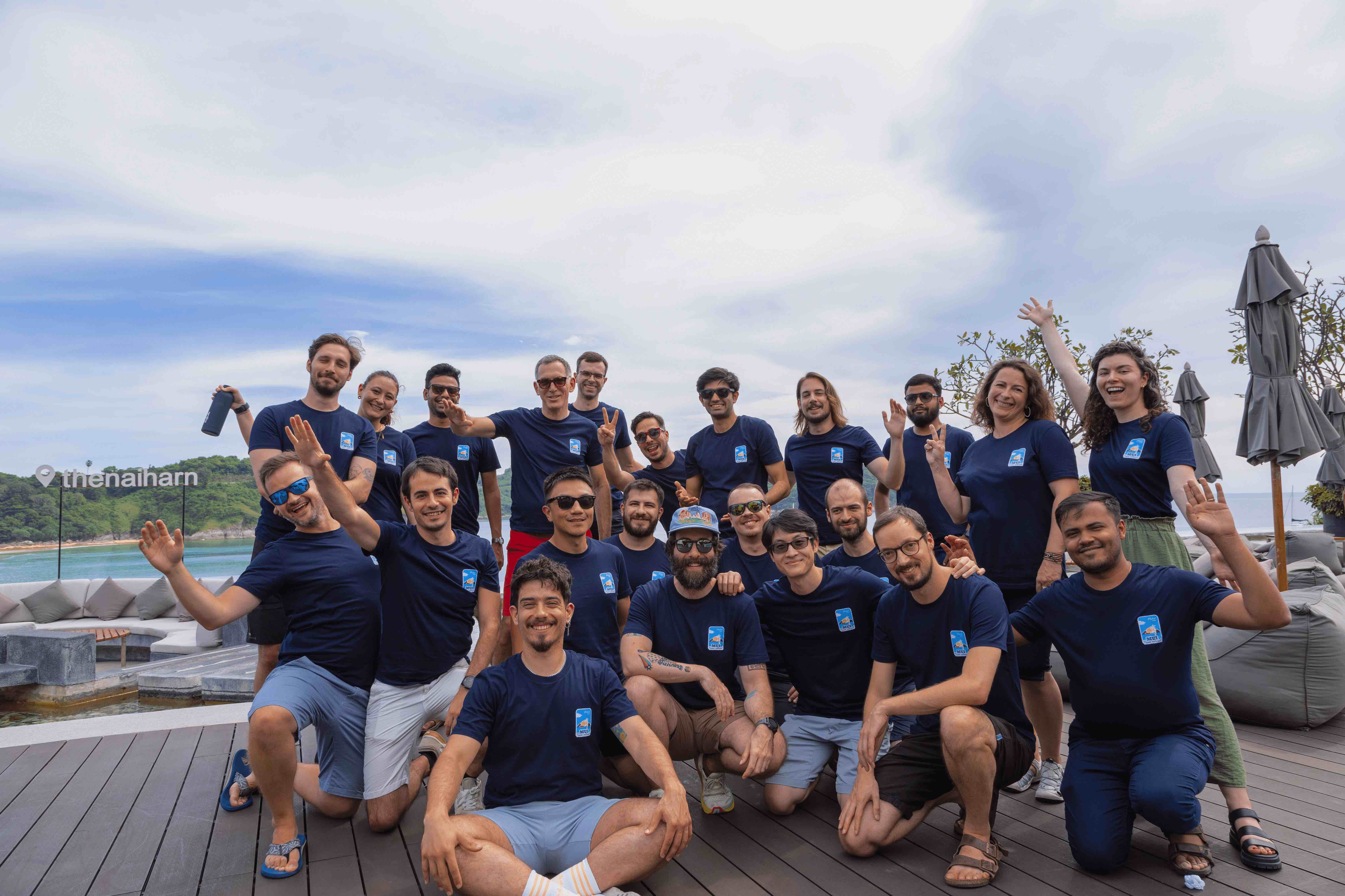 The MUI team stands together at the hotel Reflections bar. A sign to the left reads: The Nai Harn.